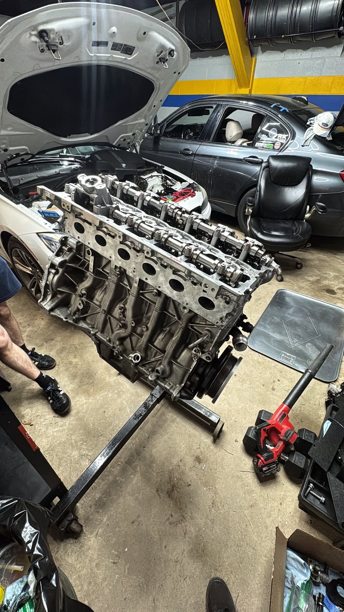 Long engine cylinder-head assembly resting on a red stand in the workshop