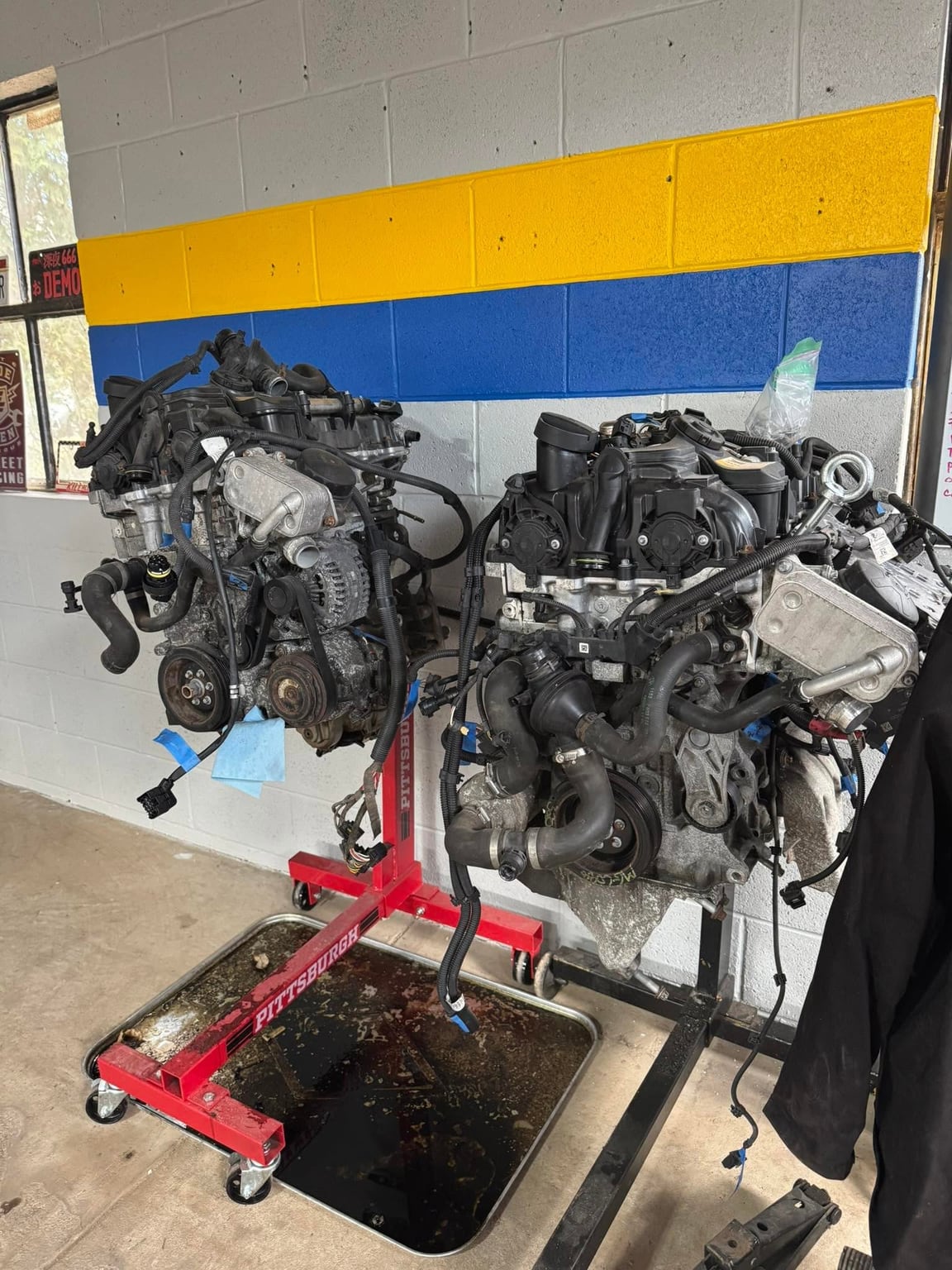 Two engines mounted on red stands inside the workshop
